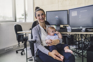 Arbeitende Mutter mit Baby auf dem Schoß, sitzend im Büro - RIBF00812