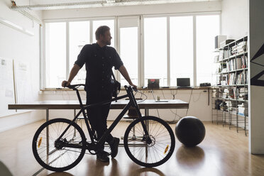 Mann steht mit seinem Fahrrad im Büro - RIBF00820