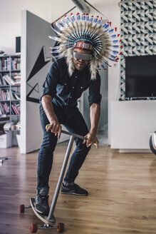 Mann mit indischem Kopfschmuck und VR-Brille im Büro, der einen Kick-Scooter benutzt - RIBF00833