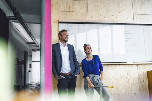 Älterer Mann und sein Assistent mit Roller, stehend im Büro vor einer weißen Tafel - RIBF00837