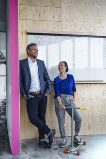 Älterer Mann und sein Assistent mit Roller, stehend im Büro vor einer weißen Tafel - RIBF00838