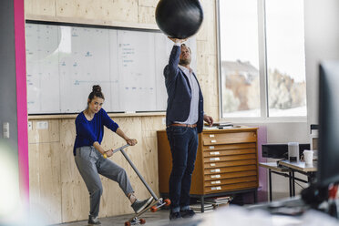 Mature man and his assistent playing with scooter, standing in office in front of white board - RIBF00842