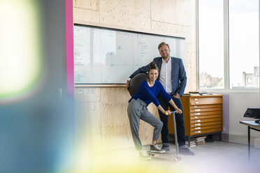 Älterer Mann und sein Assistent mit Roller, stehend im Büro vor einer weißen Tafel - RIBF00843