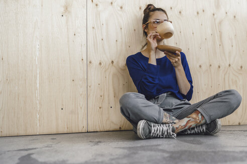 Junge Frau macht eine Pause im Büro und trinkt Kaffee aus einer Holztasse - RIBF00851
