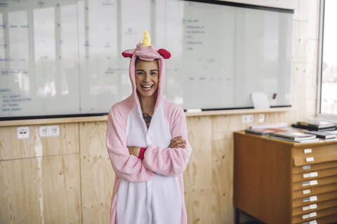 Frau mit Einhorn-Strampler, stehend vor Whiteboard, lachend, lizenzfreies Stockfoto