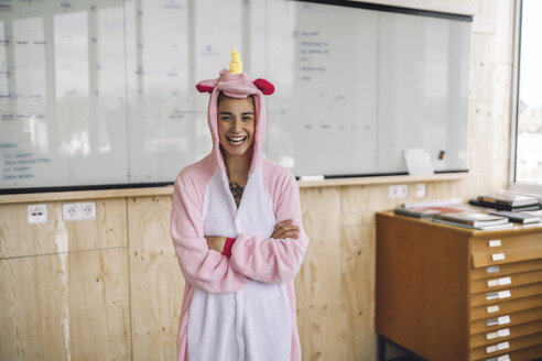 Frau mit Einhorn-Strampler, stehend vor Whiteboard, lachend - RIBF00859