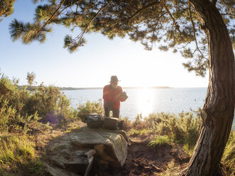 Frankreich, Bretagne, Bucht bei Perros-Guirec, älterer Wanderer mit Kamera auf Aussichtspunkt - LAF02199