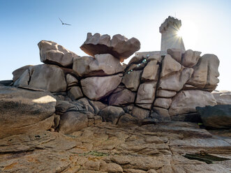 France, Bretagne, Plougrescant, Cote de Granit Rose, rock formation at Phare de Mean Ruz against the sun - LAF02201