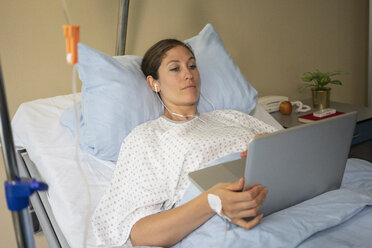 Weibliche Patientin benutzt einen Laptop, ruht sich aus und erholt sich in einem Krankenhauszimmer - FSIF03435