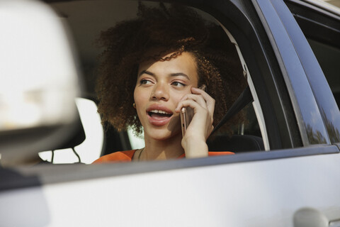 Junge Frau, die mit ihrem Smartphone telefoniert und Auto fährt, lizenzfreies Stockfoto
