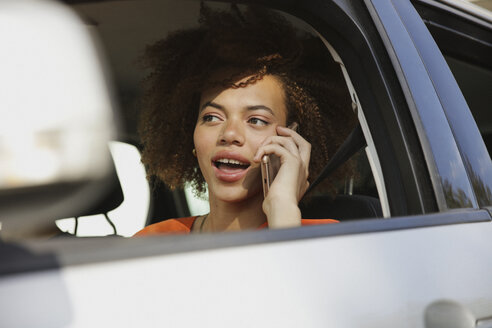 Junge Frau, die mit ihrem Smartphone telefoniert und Auto fährt - FSIF03460
