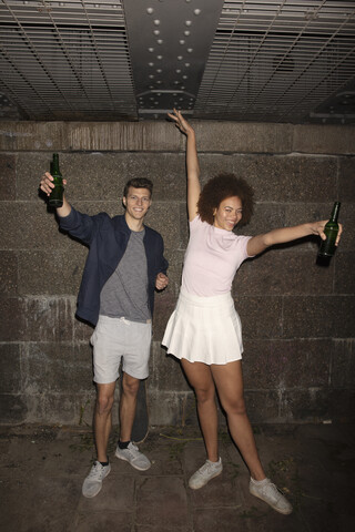 Porträt eines ausgelassenen jungen Paares beim Biertrinken im Keller, lizenzfreies Stockfoto