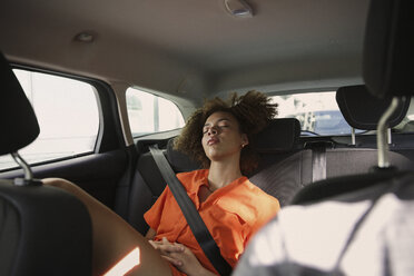 Müde junge Frau schläft auf dem Rücksitz eines Autos - FSIF03462