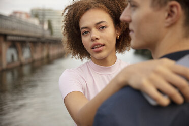 Porträt einer jungen Frau, die ihren Freund am Flussufer umarmt - FSIF03463