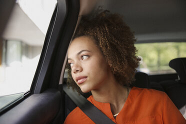 Nachdenkliche junge Frau, die im Auto sitzt und aus dem Fenster schaut - FSIF03467