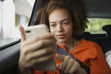 Junge Frau hört Musik mit Kopfhörern und mp3-Player im Auto - FSIF03484
