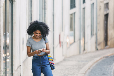 Young woman using smart phone on urban street - FSIF03508