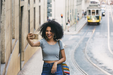 Junge Frau mit Smartphone nimmt Selfie auf städtischen Straße - FSIF03518