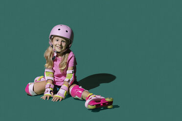 Portrait smiling girl roller skating on green background - FSIF03549