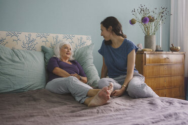 Ältere Mutter im Gespräch mit Tochter auf dem Bett - FSIF03561