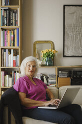 Portrait confident senior woman using laptop on living room sofa - FSIF03562