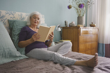 Ältere Frau liest Buch auf dem Bett - FSIF03567
