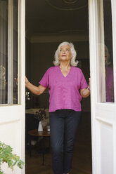 Thoughtful senior woman standing at patio doorway - FSIF03568