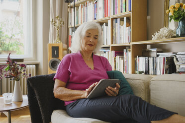 Ältere Frau mit digitalem Tablet auf dem Wohnzimmersofa - FSIF03573