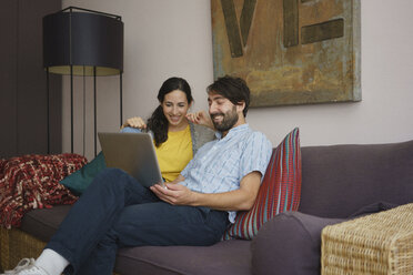 Couple using laptop on living room sofa - FSIF03576