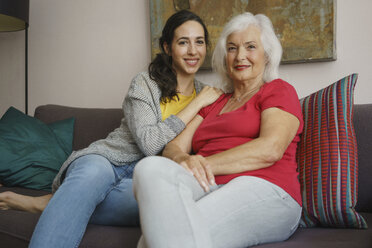 Porträt lächelnd ältere Mutter sitzt mit Tochter auf Sofa im Wohnzimmer - FSIF03581