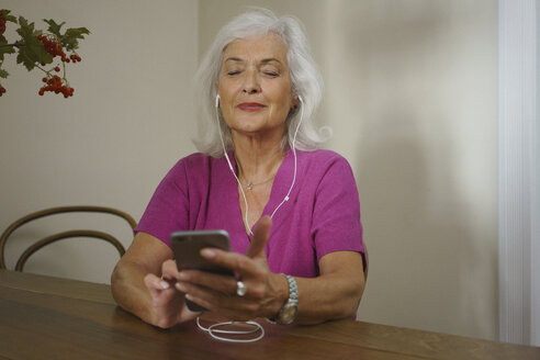 Ältere Frau, die mit Kopfhörern und mp3-Player Musik hört - FSIF03582