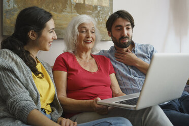 Ältere Mutter benutzt Laptop mit Tochter und Sohn auf dem Wohnzimmersofa - FSIF03586