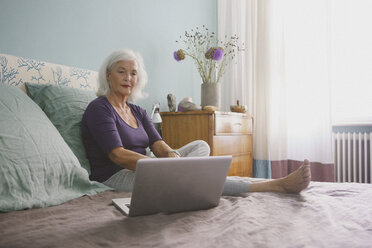 Ältere Frau mit Laptop auf dem Bett - FSIF03590