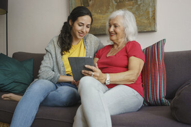 Ältere Mutter und Tochter benutzen ein digitales Tablet auf dem Wohnzimmersofa - FSIF03591