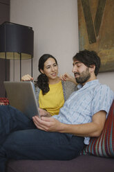 Couple using digital tablet on living room sofa - FSIF03595