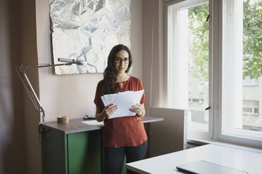 Porträt selbstbewusste Geschäftsfrau mit Papierkram im Büro - FSIF03601