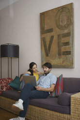 Couple using laptop on living room sofa - FSIF03603