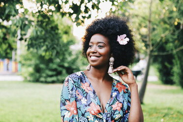 Happy young woman with pink flower in hair - FSIF03626