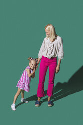 Porträt Mutter und Tochter halten Hände vor grünem Hintergrund - FSIF03632