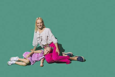 Porträt Mutter und Tochter entspannt auf grünem Hintergrund, lizenzfreies Stockfoto