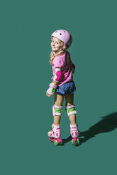 Porträt lächelnd Mädchen Rollschuhlaufen gegen grünen Hintergrund - FSIF03638
