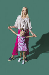 Porträt Mutter und Tochter halten Hände vor grünem Hintergrund - FSIF03653