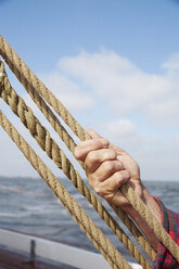 Mann hält ein Seil und stellt die Takelage eines Bootes ein - FSIF03666