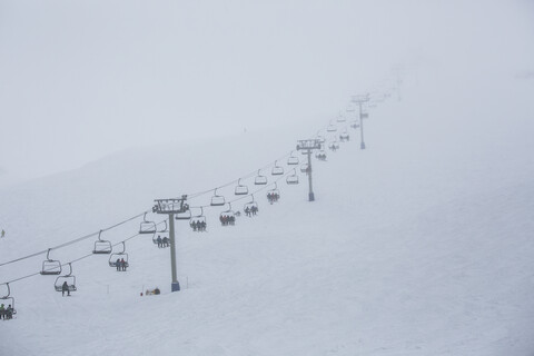 Skifahrer fahren mit dem Sessellift des Skigebiets auf den Berg, lizenzfreies Stockfoto