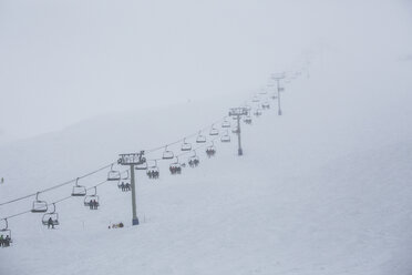 Skifahrer fahren mit dem Sessellift des Skigebiets auf den Berg - FSIF03689