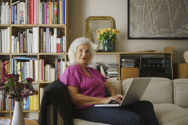 Portrait confident senior woman using laptop on living room sofa - FSIF03692