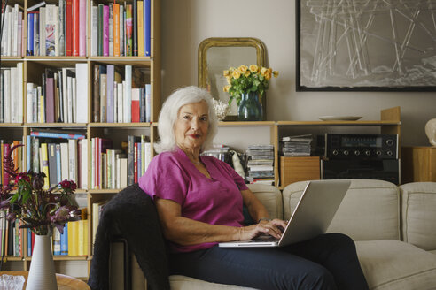 Porträt selbstbewusste ältere Frau mit Laptop auf dem Sofa im Wohnzimmer - FSIF03692