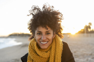 Porträt einer glücklichen Frau am Strand, die einen gelben Schal trägt - AFVF02108