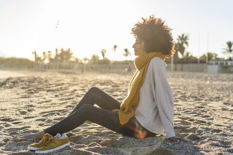 Frau sitzt bei Sonnenuntergang am Strand, lizenzfreies Stockfoto