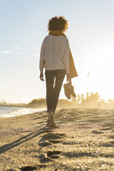 Barefoot woman on the beach, carrying her shoes - AFVF02119